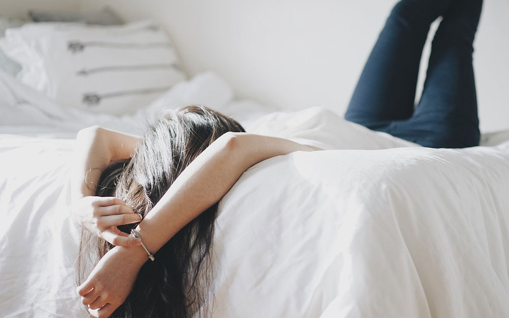 Woman lying on white duvet