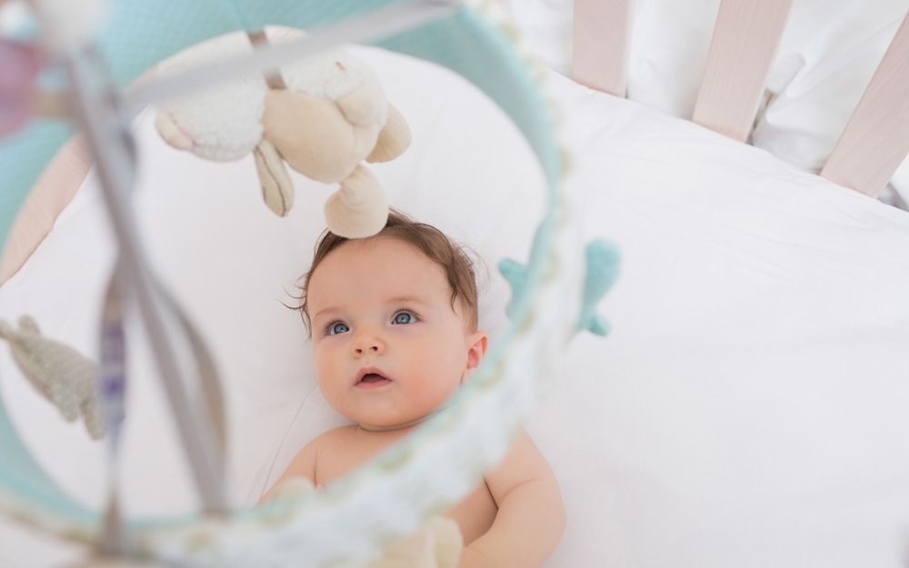 Baby in a crib lying on a cot bed mattress