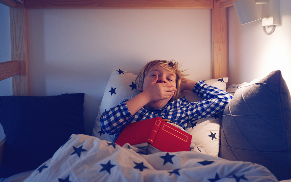 Young boy yawning in bed